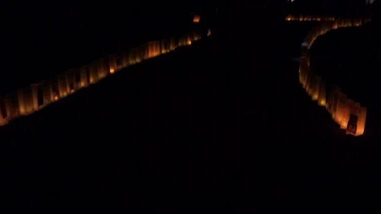 A wide path at night lit up on both sides by paper lanterns.